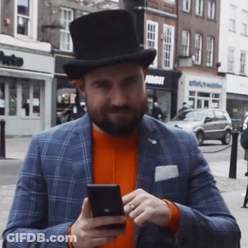 A Man Wearing A Top Hat Looking At His Phone GIF