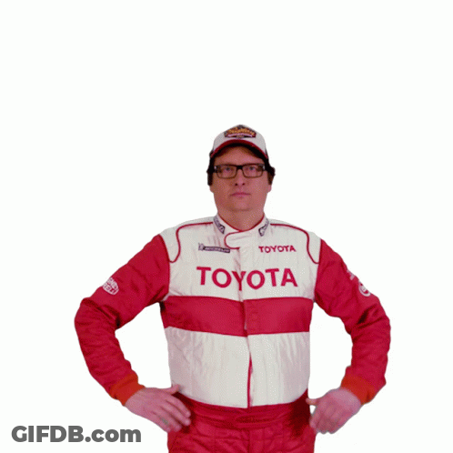 A Man Wearing A Toyota Jacket And A Superman Shirt Holds His Fist Up In The Air GIF