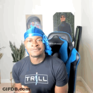 A Man Wearing A Trill T-Shirt Is Sitting In A Gaming Chair GIF