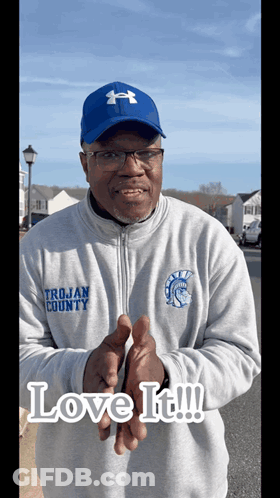 A Man Wearing A Trojan County Sweatshirt And A Blue Hat GIF