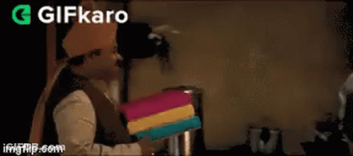 A Man Wearing A Turban Is Holding A Gift Box And Says `` Happy Anniversary '' . GIF