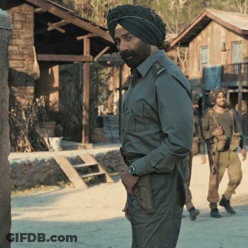 A Man Wearing A Turban Stands In Front Of A Building GIF