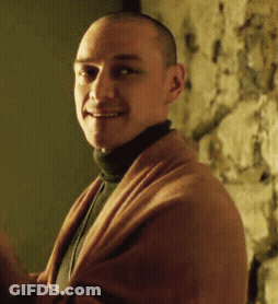 A Man Wearing A Turtleneck And A Brown Sweater Smiles For The Camera GIF
