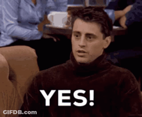 A Man Wearing A Turtleneck Sweater Is Sitting On A Couch And Saying Yes . GIF