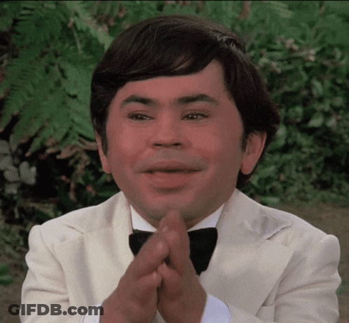 A Man Wearing A Tuxedo And Bow Tie Is Clapping His Hands GIF