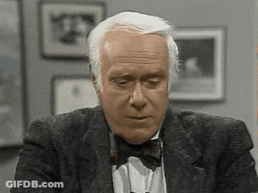 A Man Wearing A Tuxedo And Bow Tie Is Looking Down . GIF