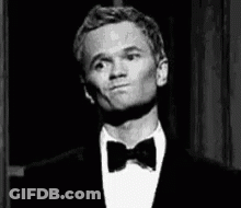 A Man Wearing A Tuxedo And Bow Tie Is Making A Funny Face . GIF