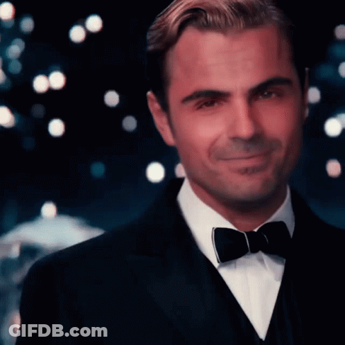 A Man Wearing A Tuxedo And Bow Tie Smiles For The Camera GIF