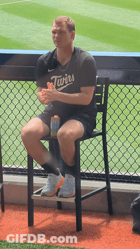 A Man Wearing A Twins Jersey Sits On A Chair GIF