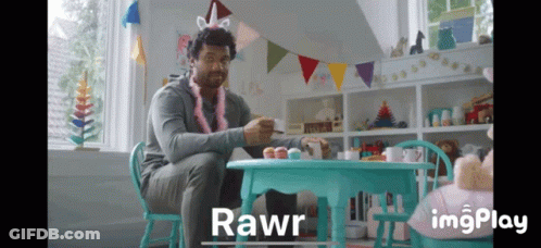 A Man Wearing A Unicorn Headband Sits At A Table With Cupcakes And Says Rawr GIF