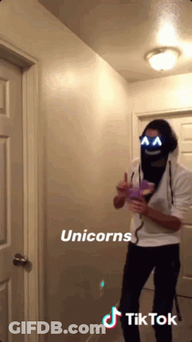 A Man Wearing A Unicorn Mask Is Standing In A Hallway Next To A Door GIF