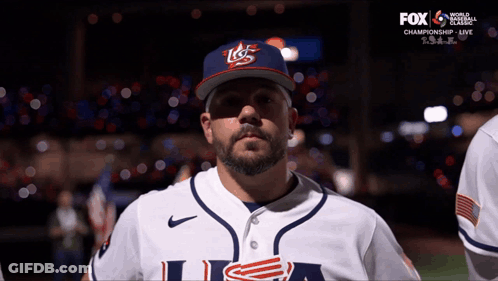 A Man Wearing A Usa Baseball Uniform Stands In Front Of A Fox Broadcast GIF