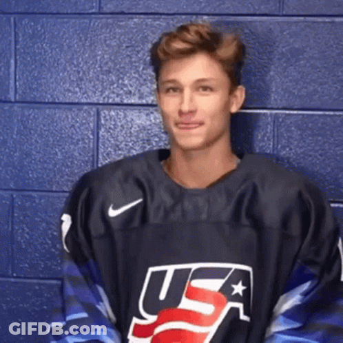A Man Wearing A Usa Jersey Is Standing In Front Of A Blue Wall . GIF