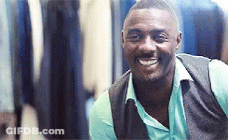 A Man Wearing A Vest And A Blue Shirt Is Smiling And Looking At The Camera . GIF