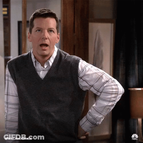 A Man Wearing A Vest And A Plaid Shirt Has His Hands On His Hips GIF