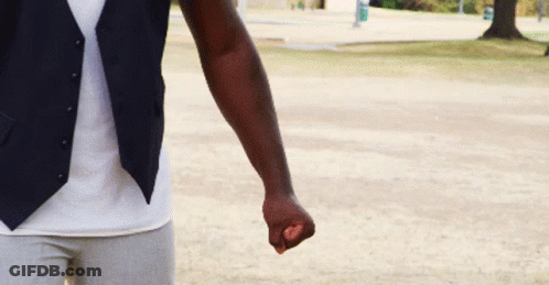 A Man Wearing A Vest And A White Shirt Is Holding A Purple Object In His Fist . GIF