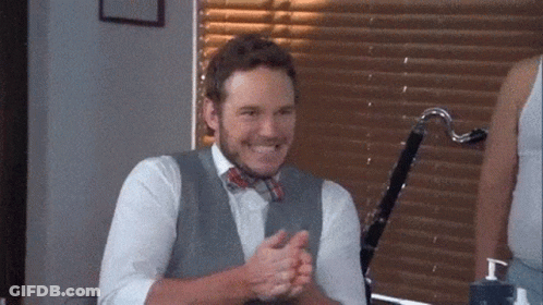 A Man Wearing A Vest And Bow Tie Is Clapping His Hands . GIF
