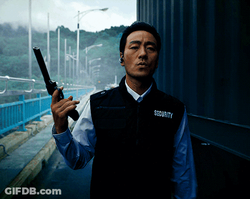 A Man Wearing A Vest That Says Security On It Holds A Gun GIF