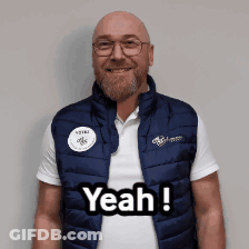 A Man Wearing A Vest That Says Yeah Is Smiling GIF