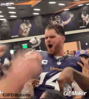 A Man Wearing A Vikings Jersey Is Being Held Up By Fans GIF