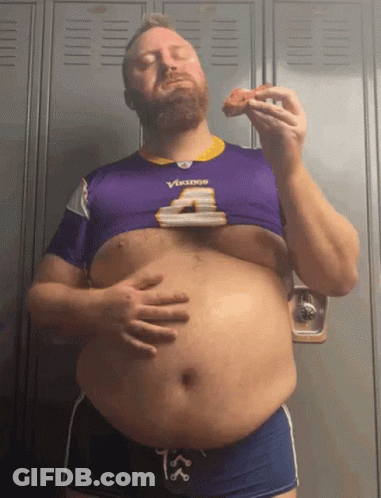 A Man Wearing A Vikings Jersey Is Eating A Slice Of Pizza GIF