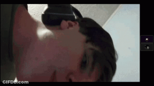 A Man Wearing A Virtual Reality Headset Is Laying On His Back GIF