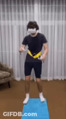 A Man Wearing A Virtual Reality Headset Is Standing On A Blue Mat In A Living Room . GIF