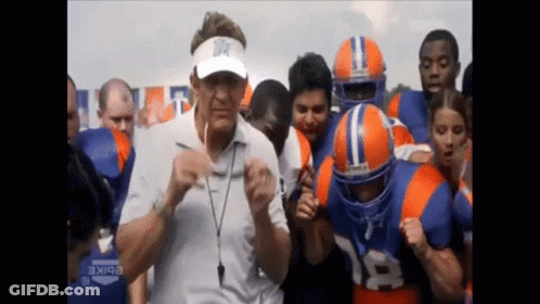 A Man Wearing A Visor With A Star On It Is Surrounded By Football Players GIF