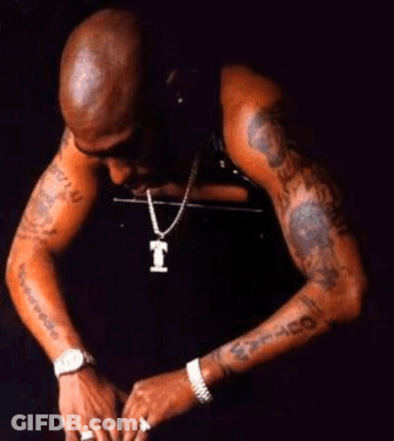 A Man Wearing A Watch And A Necklace With A Letter T On It GIF