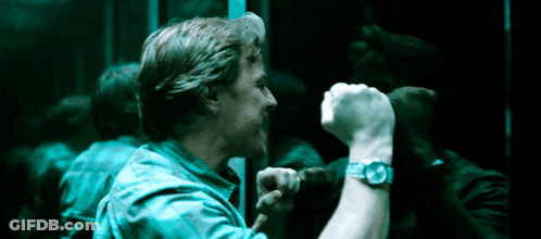 A Man Wearing A Watch Holds His Fist Up In Front Of A Mirror . GIF