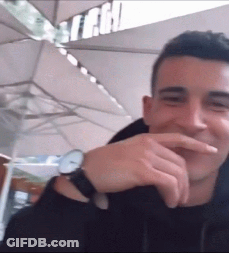 A Man Wearing A Watch Is Laughing And Covering His Mouth GIF