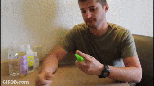 A Man Wearing A Watch Is Spraying Something On His Wrist While Sitting At A Table GIF