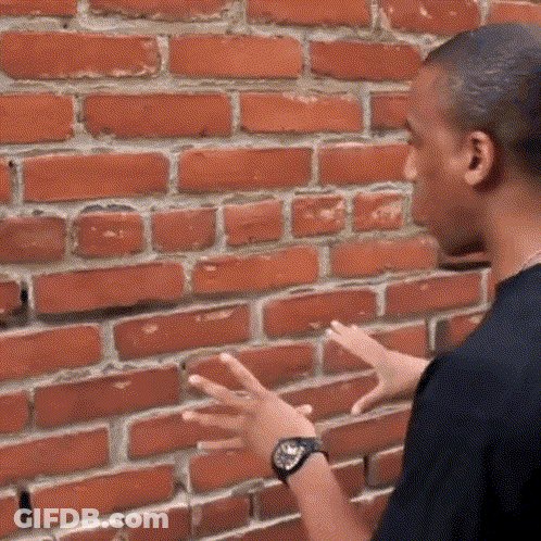 A Man Wearing A Watch Is Standing In Front Of A Brick Wall With His Hands Outstretched GIF