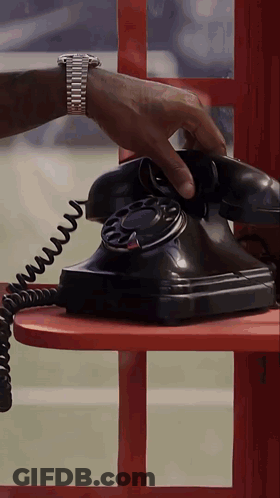A Man Wearing A Watch Is Talking On A Black Telephone GIF