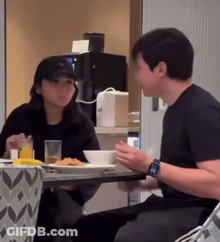 A Man Wearing A Watch Sits At A Table With A Woman Eating Food GIF