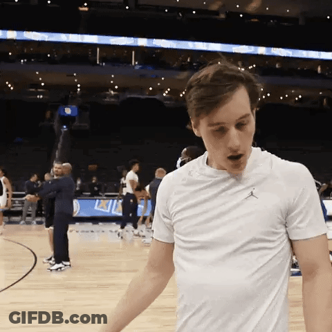 A Man Wearing A White Air Jordan T-Shirt Is Standing On A Basketball Court GIF