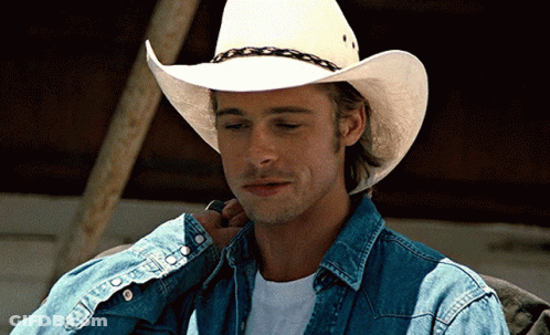 A Man Wearing A White Cowboy Hat And A Denim Shirt GIF