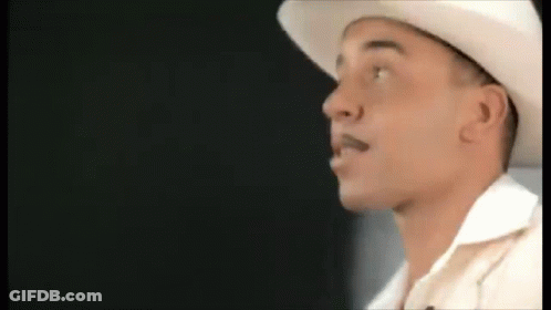 A Man Wearing A White Cowboy Hat And A White Shirt Is Looking To The Side . GIF