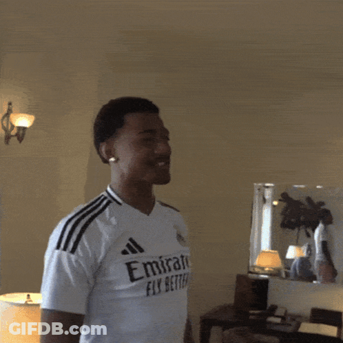A Man Wearing A White Emirates Fly Better Shirt Is Making A Heart Shape With His Hands GIF