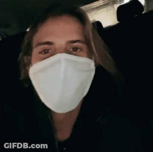 A Man Wearing A White Face Mask In A Dark Room GIF