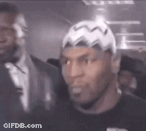 A Man Wearing A White Hat And A Black Shirt Is Standing Next To A Man In A Suit . GIF
