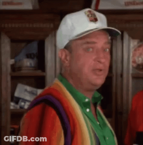 A Man Wearing A White Hat And A Colorful Sweater Is Standing In A Room . GIF