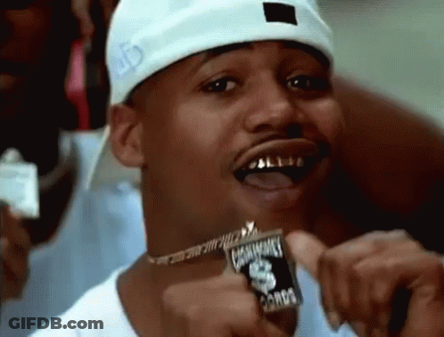 A Man Wearing A White Hat And A Necklace Is Holding A Coin In His Hand . GIF