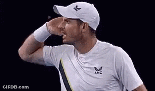 A Man Wearing A White Hat And A White Shirt Is Holding His Hand To His Face . GIF