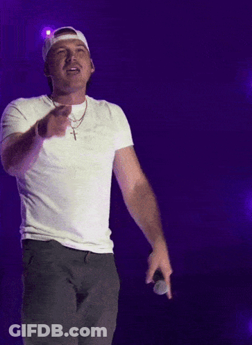 A Man Wearing A White Hat And A White T-Shirt Holds A Microphone GIF