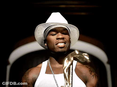 A Man Wearing A White Hat And A White Tank Top Holds A Gold Statue GIF
