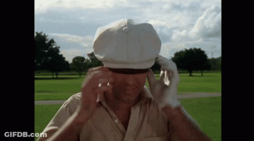 A Man Wearing A White Hat And Gloves Is Standing In A Park GIF