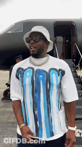 A Man Wearing A White Hat And Sunglasses Is Standing In Front Of A Plane GIF