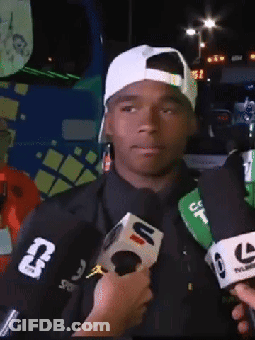 A Man Wearing A White Hat Is Being Interviewed By A Reporter Wearing A Jacket With The Letter T On The Sleeve GIF