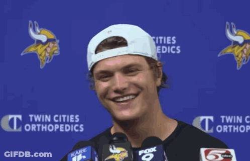 A Man Wearing A White Hat Is Smiling In Front Of A Blue Backdrop That Says Twin Cities Orthopedics GIF